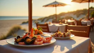 Terrasse d'un restaurant effet mer à Fort Mahon avec plateau de fruits de mer frais posé sur une table en bois face aux dunes et à l'Atlantique